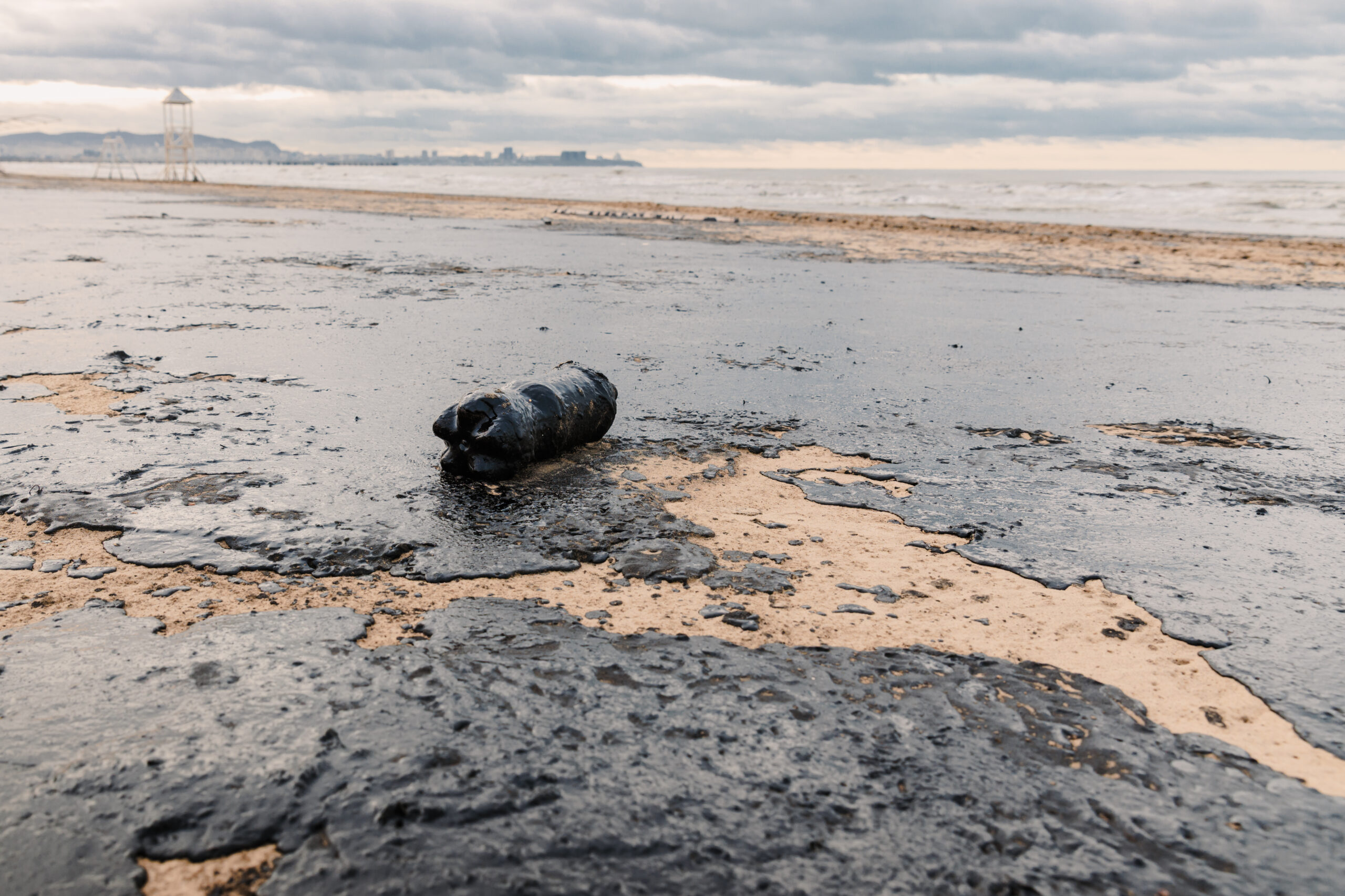 Lupa Ambiental | Vazamento de óleo polui praia arenosa com resíduos plásticos, destacando desastre ambiental e crise de poluição marinha em Anapa.